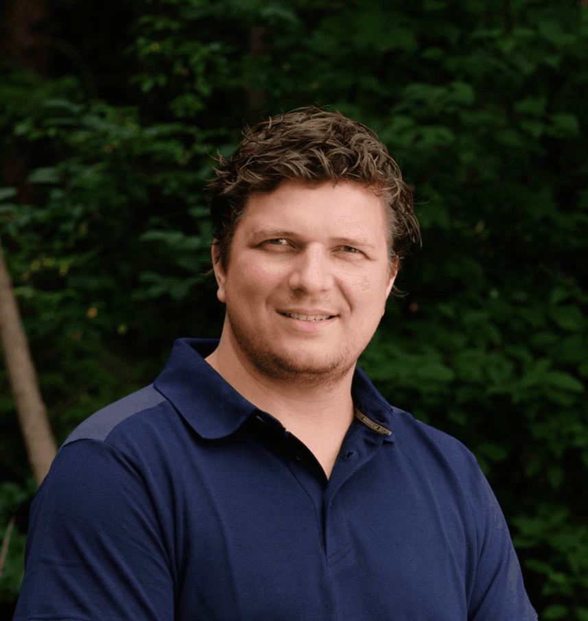 Mann mit kurzem Haar im Freien vor grünem Hintergrund